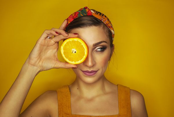 girl posing with an orange - a picture used in article about vitamin c health benefits