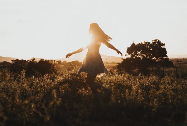 a woman in a dress swirling around in a field on sunset
