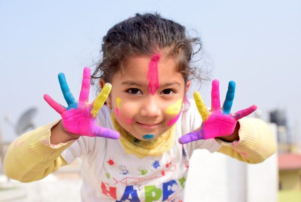 a girl kid with paint on her hands in different colors - picture is used in article about omega 3 health benefits for kids