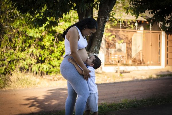 a pregnant woman looking down at her other child, that is hugging her belly - this picture is used in article about omega 3 health benefits for pregnancy