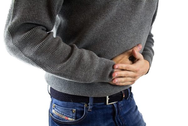 a man holding his stomach in a white background - picture used in article on omega 3 benefits for gut issues