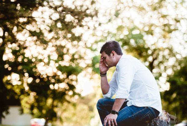 a man sitting down in a park because he feels fatigued - image used in article for chronic fatigue review