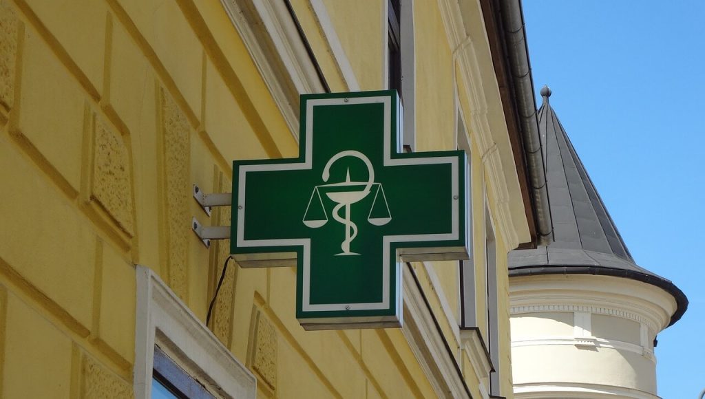 pharmacy sign on a yellow building - used in article on medicine supply bottlenecks