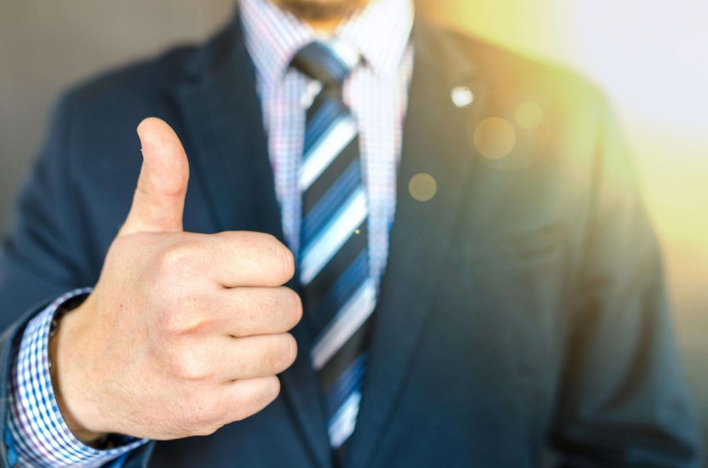 the torso of a man in a fancy suit giving a thumbs up, used in article on quality management