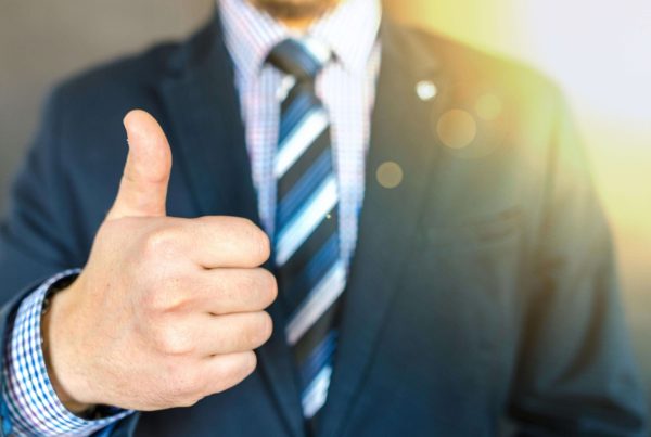 the torso of a man in a fancy suit giving a thumbs up, used in article on quality management