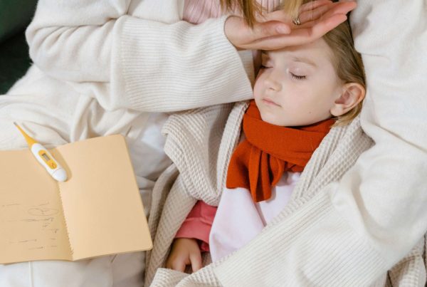 a sick child lying in his mother's hands used in article on use of antibiotic amoxicillin