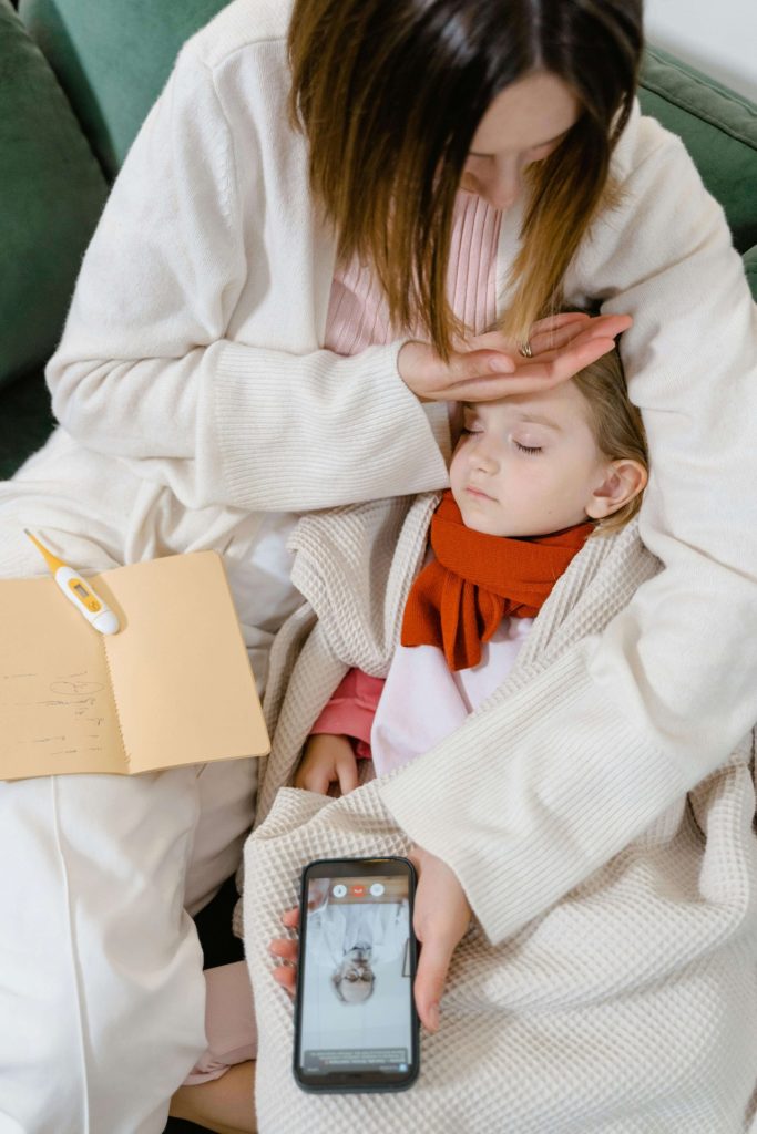 a sick child lying in his mother's hands used in article on use of antibiotic amoxicillin